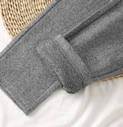 Turned-up hem on grey herringbone-textured trousers.