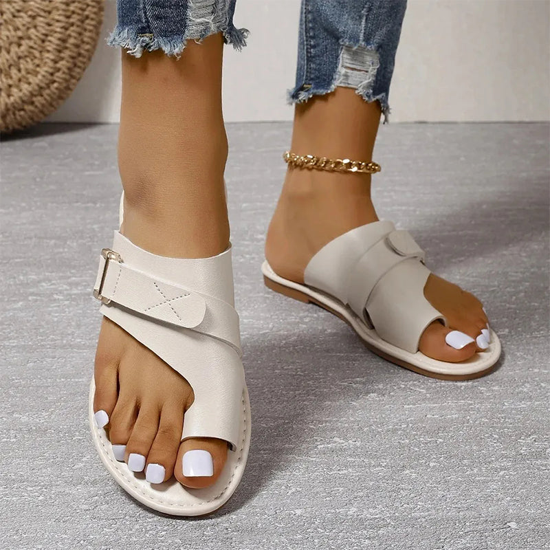 White toe-loop sandals with adjustable straps and metallic side buckles.
