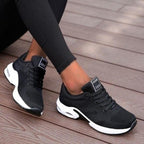 Black lace-up trainers with white soles and tongue labels.