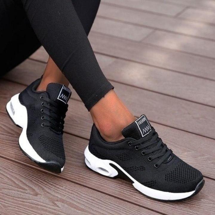 Black lace-up trainers with white soles and tongue labels.
