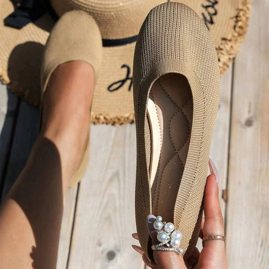 Khaki flat shoes shown worn and held beside a woven hat.
