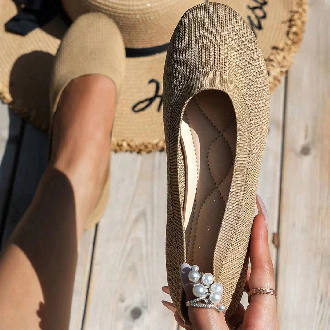 Khaki flat shoes shown worn and held beside a woven hat.