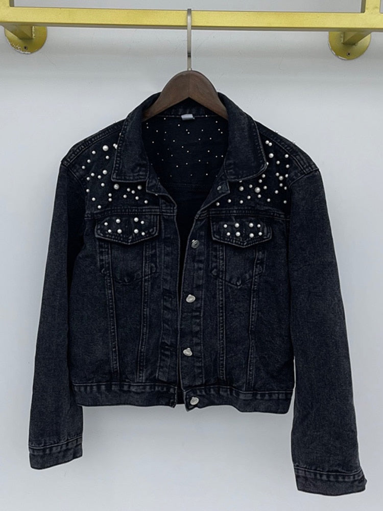 Black denim jacket shown from the front on a wooden hanger.