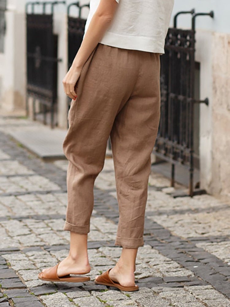 Rear angled view of khaki trousers with rolled hems.