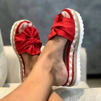 Red bow sandals with broad front straps and white soles.