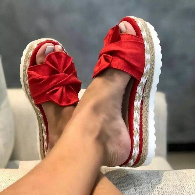 Red bow sandals with broad front straps and white soles.