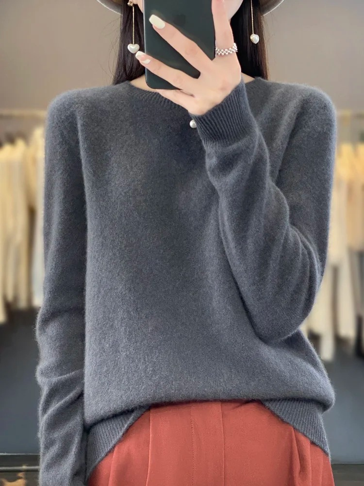 Grey crew-neck jumper worn with rust-coloured trousers.