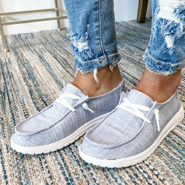 Grey lace-up shoes with stitched toe panels and pale soles.