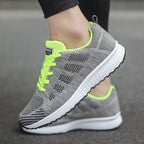 Grey and bright green trainer showing its mesh pattern and white sole.