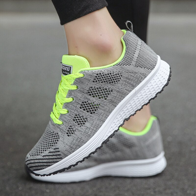 Grey and bright green trainer showing its mesh pattern and white sole.