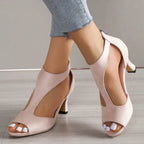 Pink peep-toe heels with curved side cutouts and shaped heels, worn with cropped jeans.