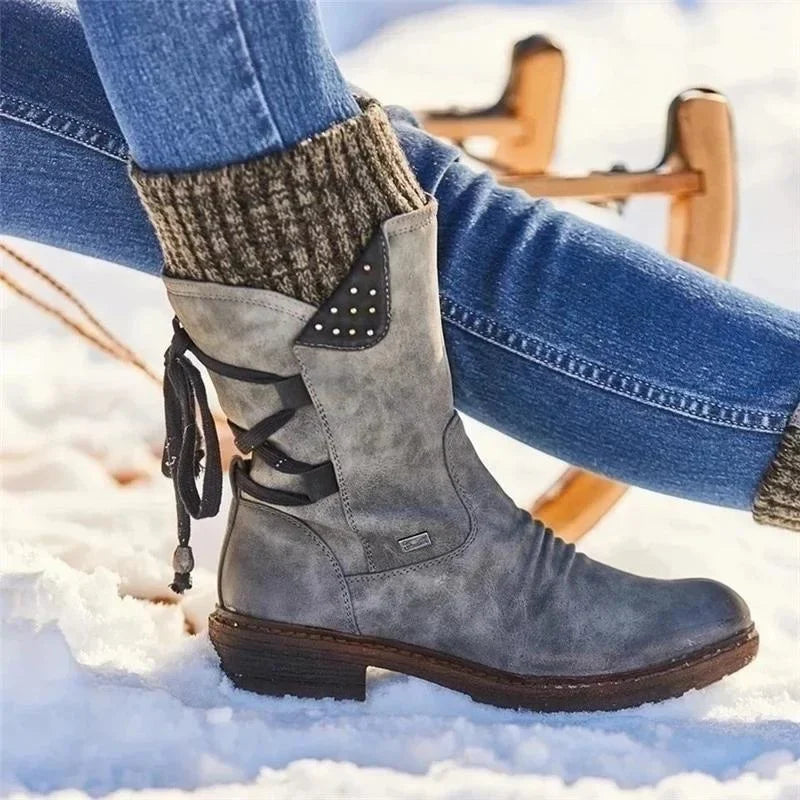 Grey knit-cuff boots worn with jeans on snow.