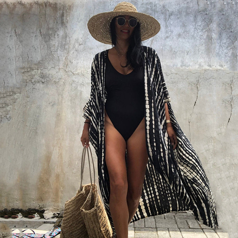Long black-and-white printed cover-up worn open over a black swimsuit.