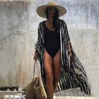 Long black-and-white printed cover-up worn open over a black swimsuit.