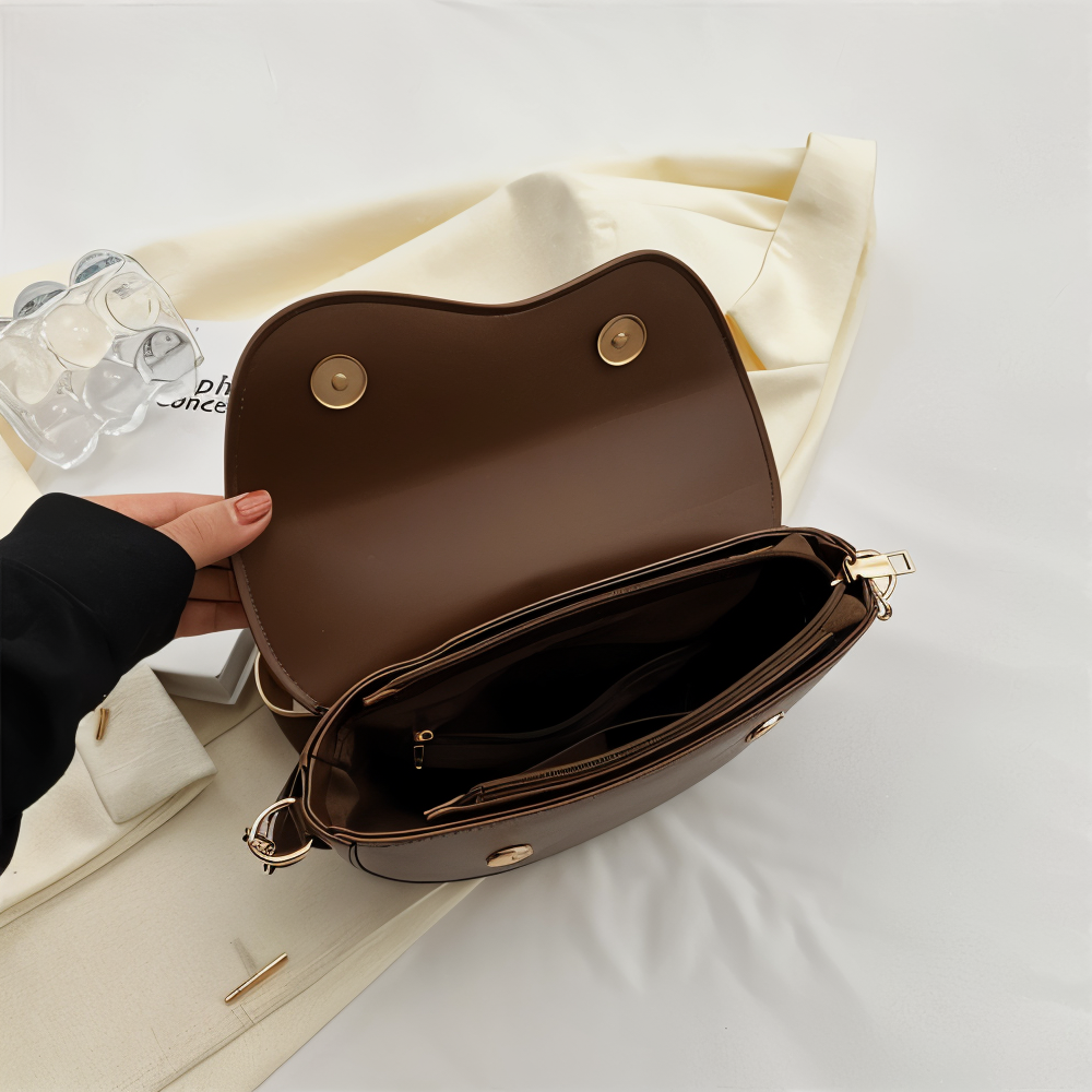 Open brown shoulder bag showing two magnetic flap fastenings and interior pockets.