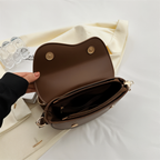 Open brown shoulder bag showing two magnetic flap fastenings and interior pockets.