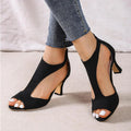 Black peep-toe heels shown from the front with ankle-high uppers and open sides.