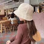 Side view of a cream textured bucket hat worn by a seated woman.