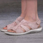 Pink sandals with crossed front cords, shown being worn.