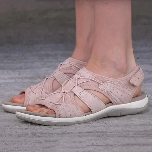 Pink sandals with crossed front cords, shown being worn.