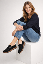 Black open-heel clogs shown on a seated model.