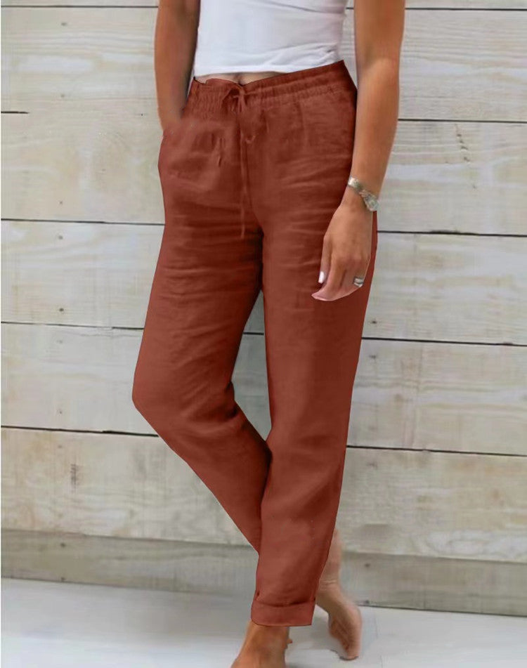 Rust-red trousers with side pockets and rolled hems.