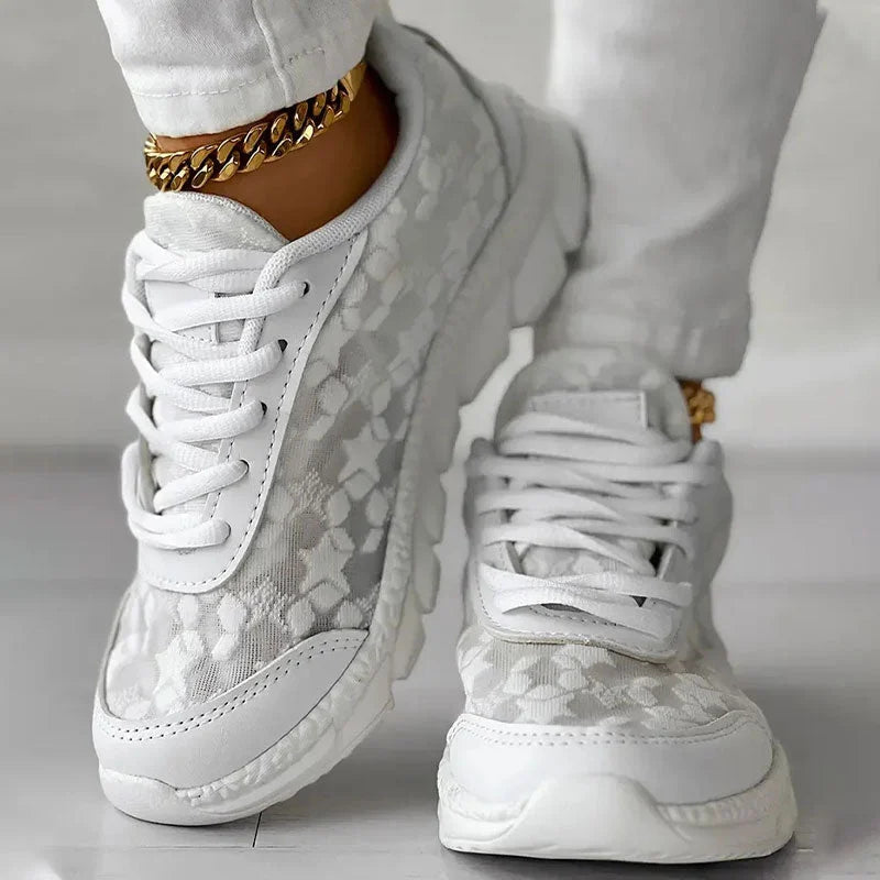 White floral trainers worn with white trousers.