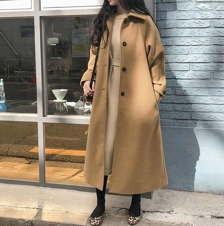 Tan long coat shown open with dark upper-front buttons.
