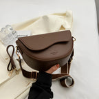 Coffee-brown shoulder bag with a curved flap and adjustable strap.