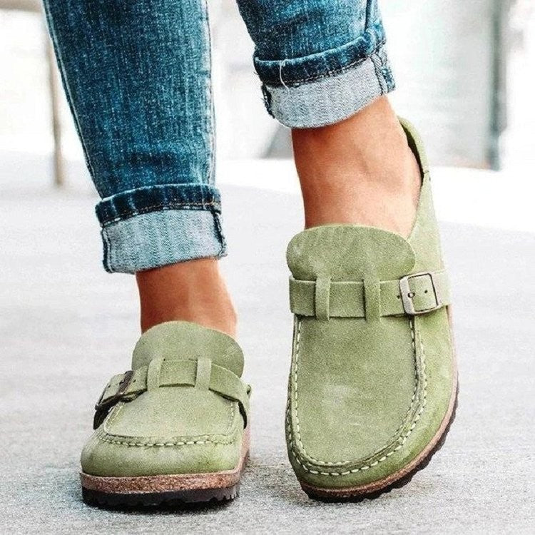 Light green clogs with rounded toes and metal buckles.