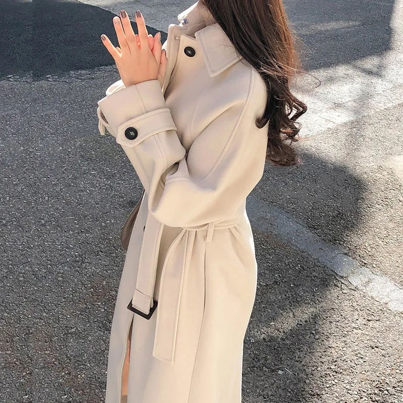 Close-up of beige coat with a point collar and buttoned cuff tab.