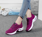 Purple lace-up trainers worn with jeans beside a magazine.