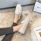Cream plush loafer-style slippers worn with jeans, showing the front bands and textured uppers.