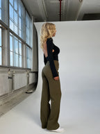 Side view of olive-green trousers worn near a window.