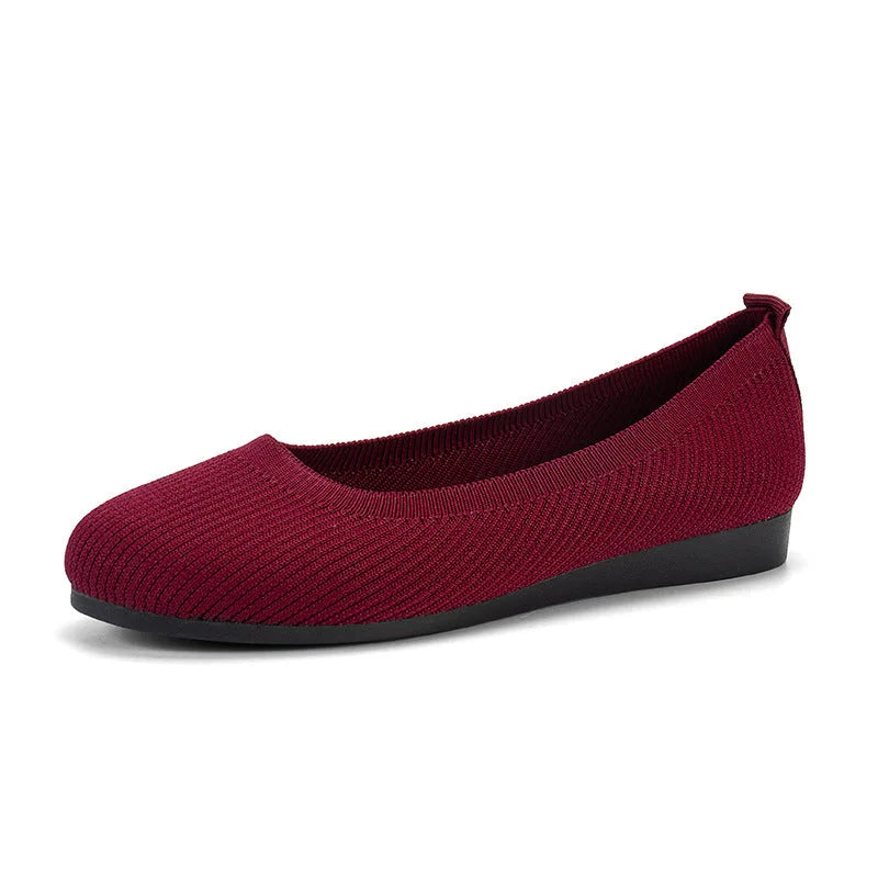 Burgundy flat shoe with a fine textured upper and low black sole.