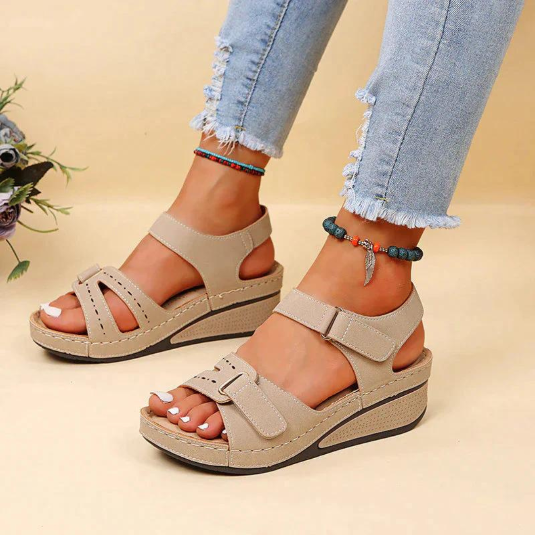 Beige wedge sandals with rectangular strap tabs.