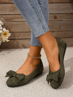Dark green flats with layered bows worn with jeans.