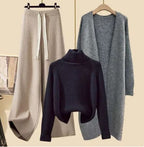 Navy roll-neck jumper with beige wide-leg trousers and a grey knit jacket.