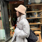 Woman wearing a beige bucket hat with a light padded jacket.