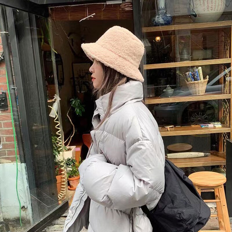 Woman wearing a beige bucket hat with a light padded jacket.